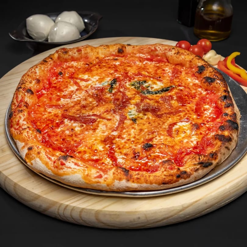 A freshly baked pizza with melted cheese and tomato sauce on a wooden board with ingredients.